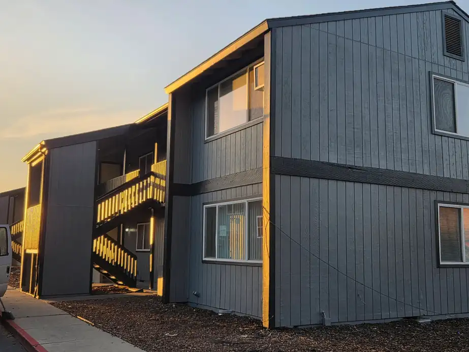 Slate grey apartment block with black trim lit by low sunset light