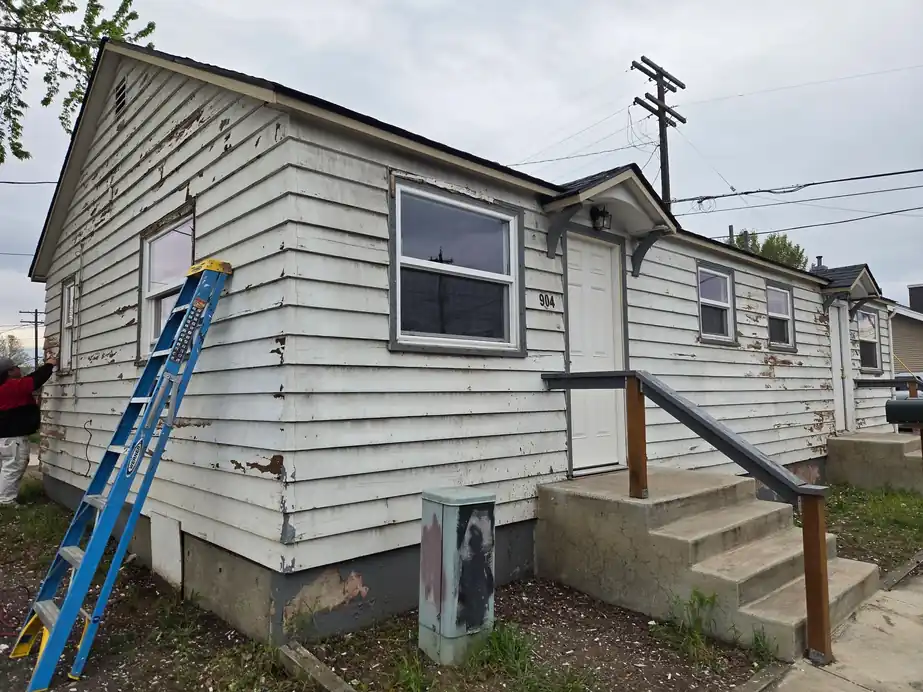 Before shot of a house with peeling white lap siding