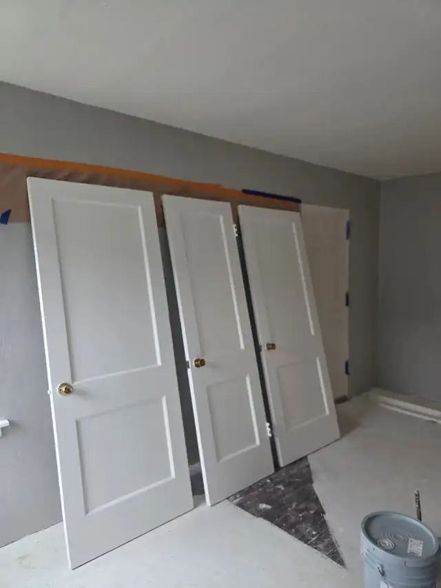 Three freshly painted panel doors leaning against a wall